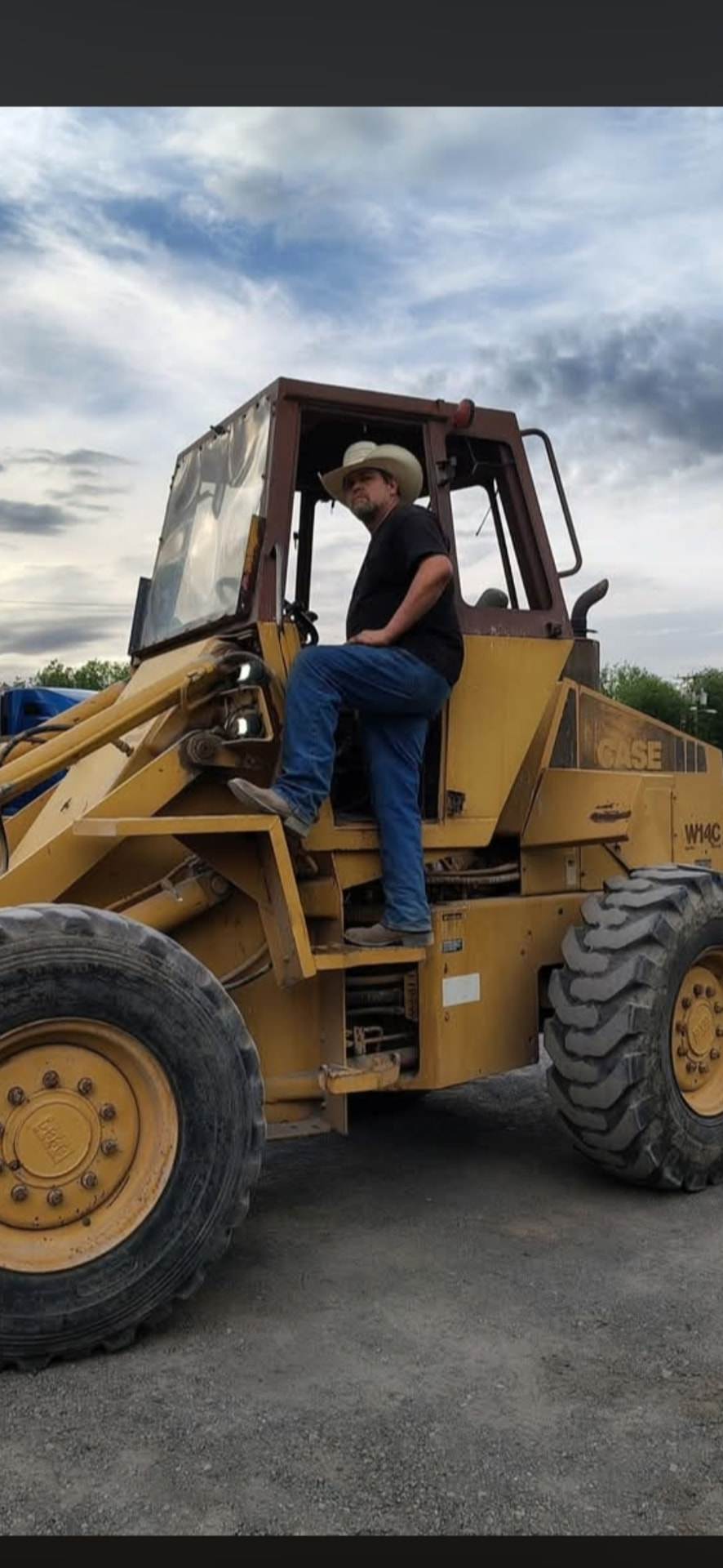 Christopher Sneed, founder of Blue Collar Empire, standing on a Case W14C wheel loader at a jobsite